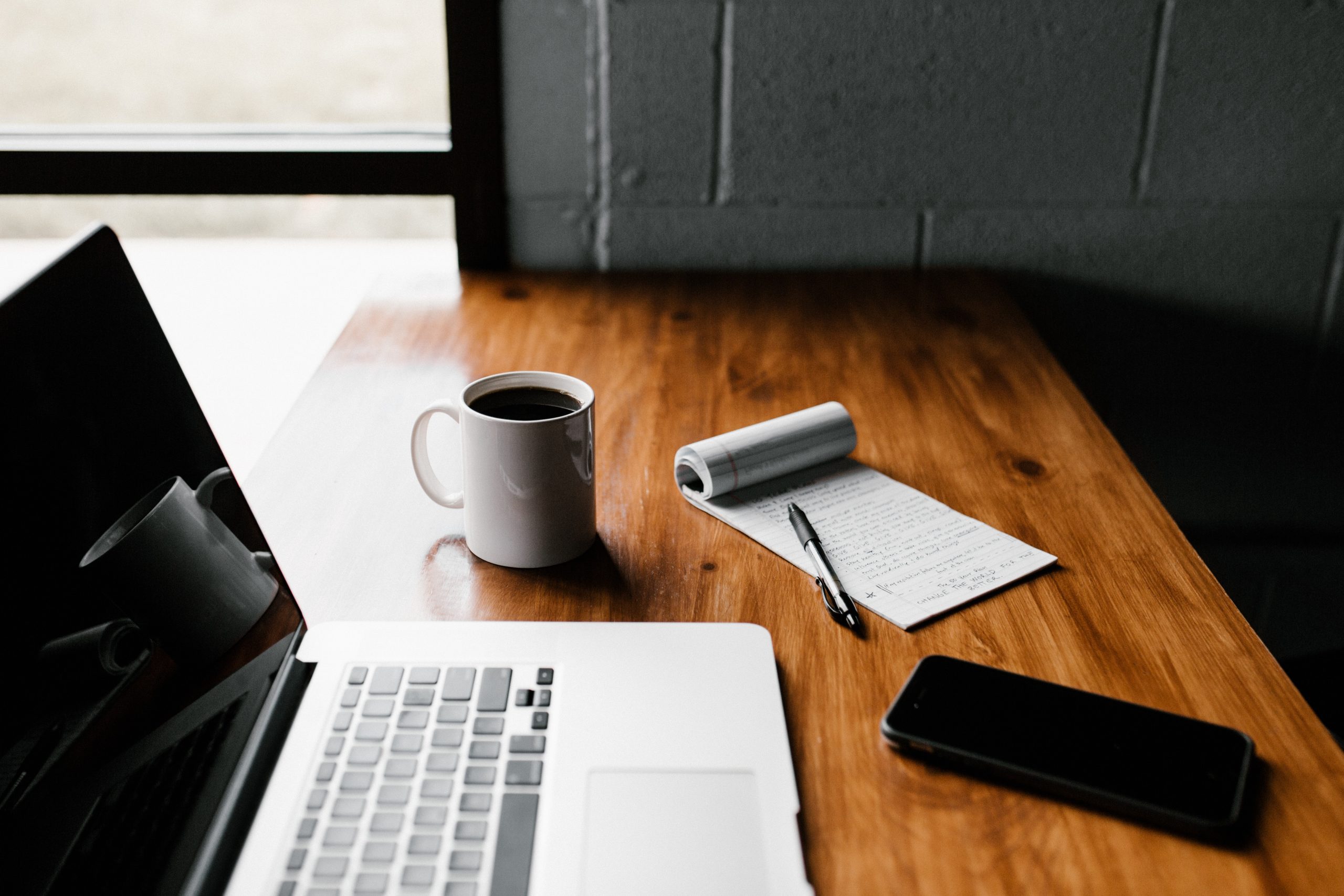 mesa con pc, café, libreta y mobil